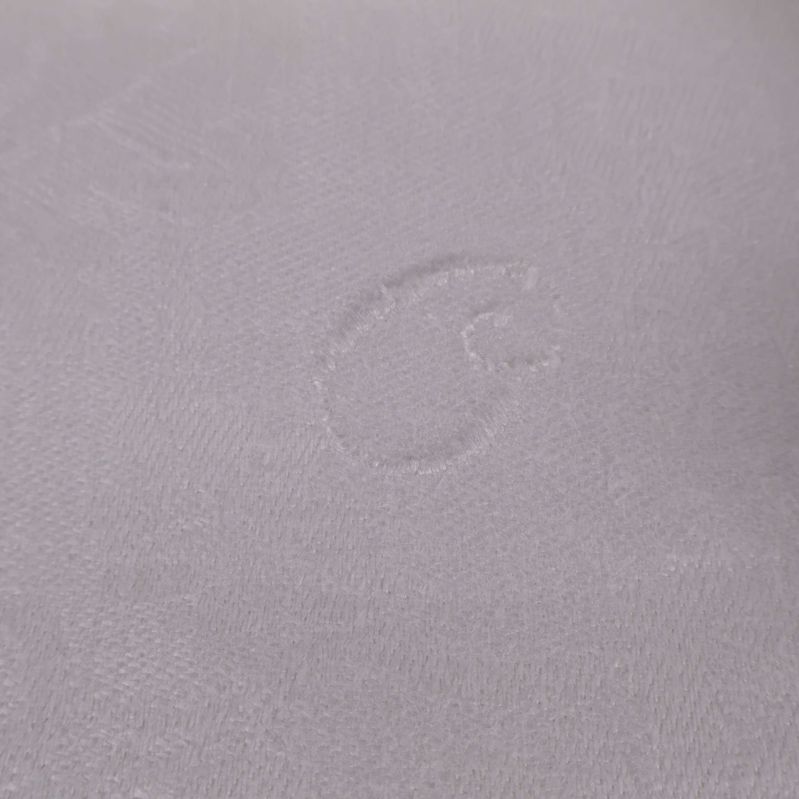 Detaljerad vävd märkning i vit duk