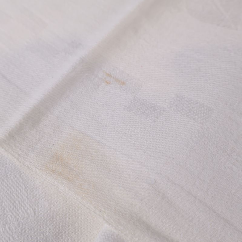 Ljusa fläckar och mindre missfärgningar på duk i närbild