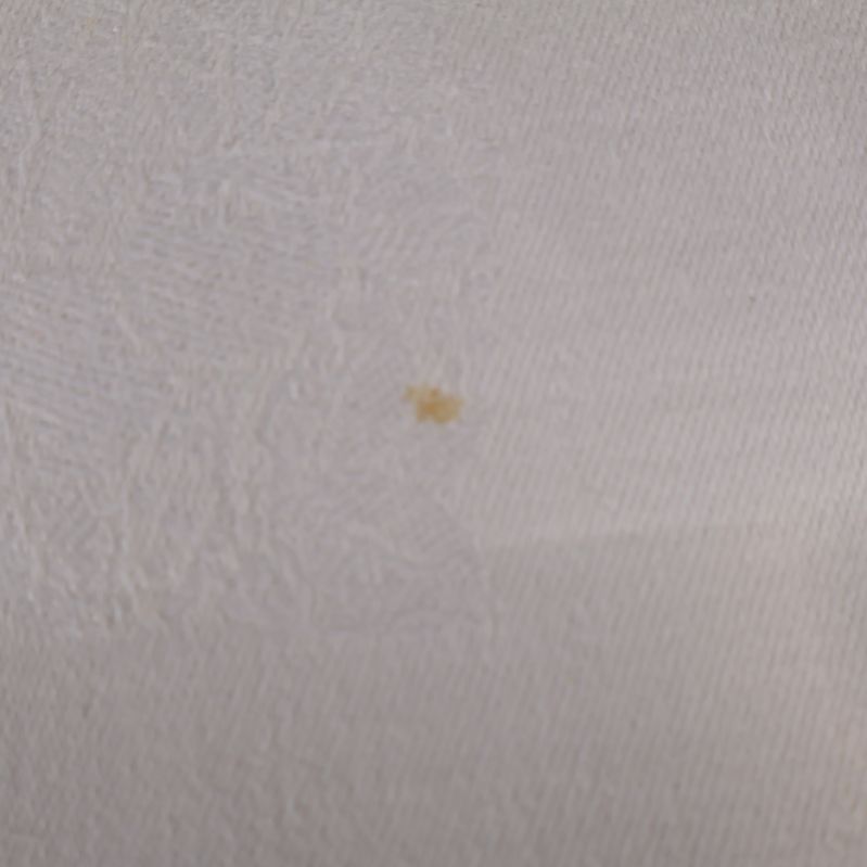 Närbild på liten synlig fläck på vit duk