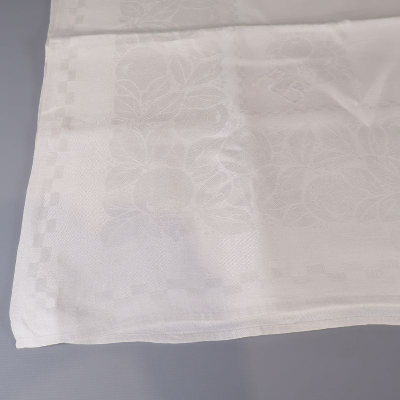Närbild på vit duk med invävt blommönster