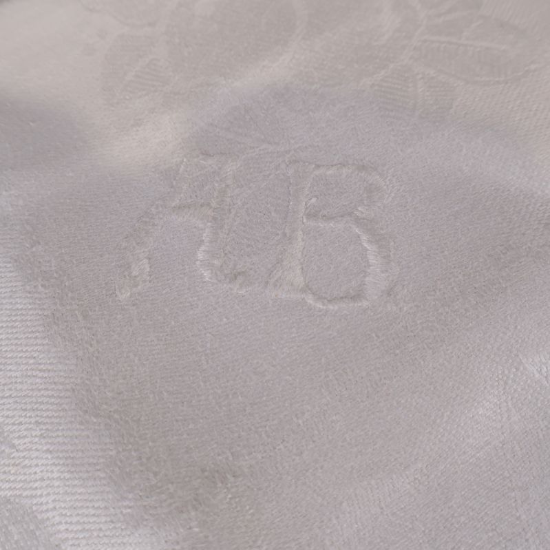 Närbild på initialerna AB invävda i duken