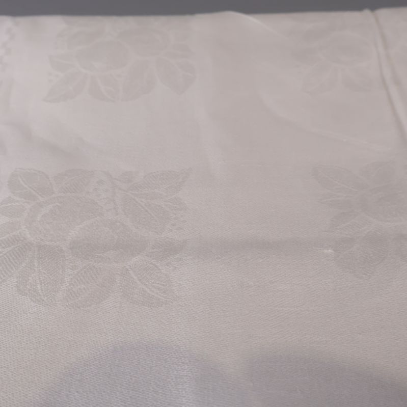 Detaljbild av vit duk med blommönster och veck