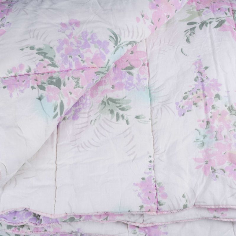 Närbild på täckets hörn med blommor i rosa och lila