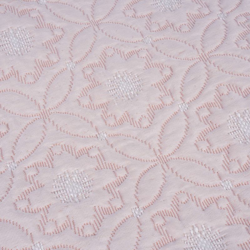 Närbild på quiltat blommönster i ljust tyg