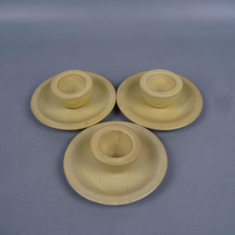 Tre gula äggkoppar med tillhörande fat ovanifrån