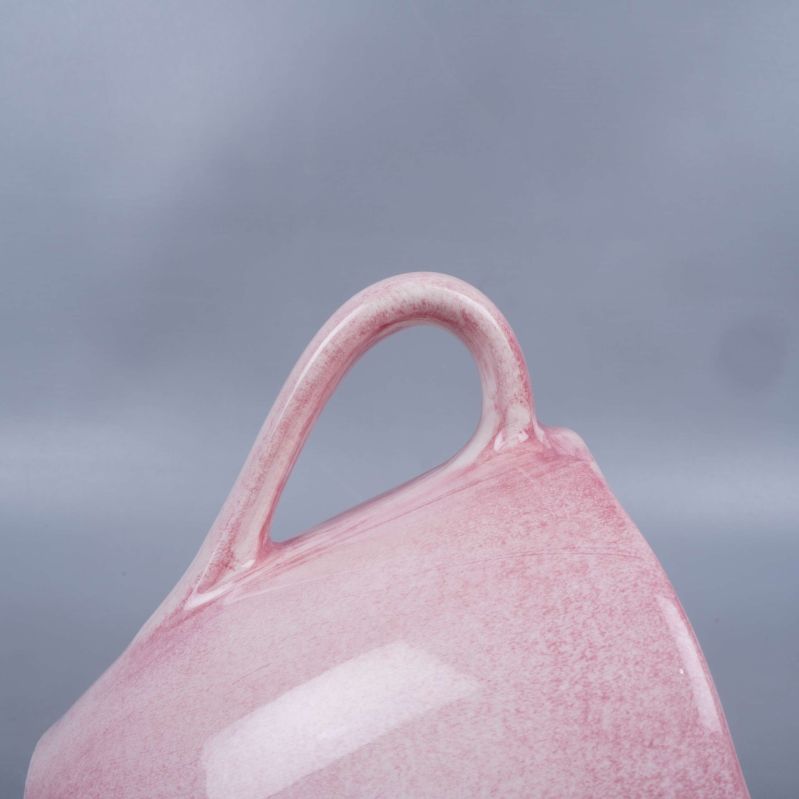 Närbild på koppens böjda handtag i rosa glasyr