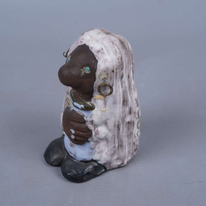 Sida av keramisk figur med örhängen och armband