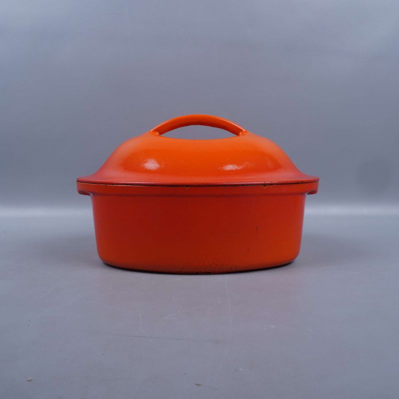 Orange gryta med lock sedd rakt bakifrån