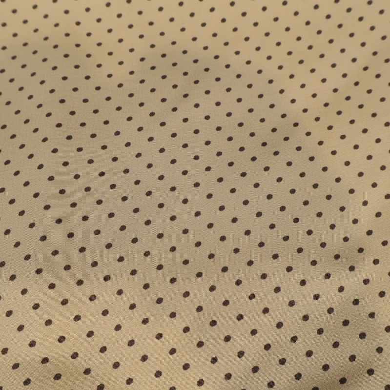 Närbild på beige tyg med små mörka prickar