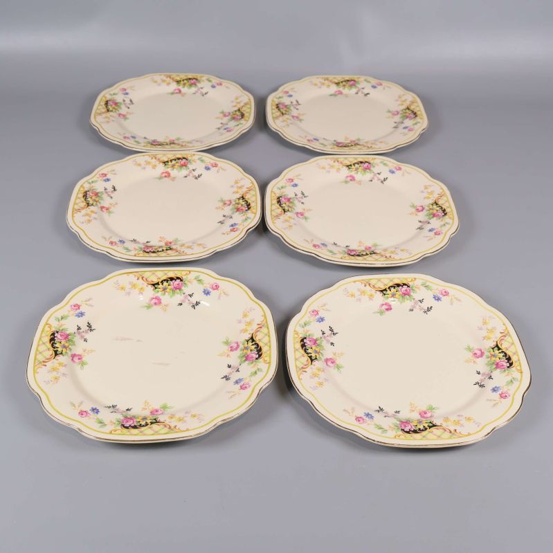 Sex assietter med blommönster utlagda på rad