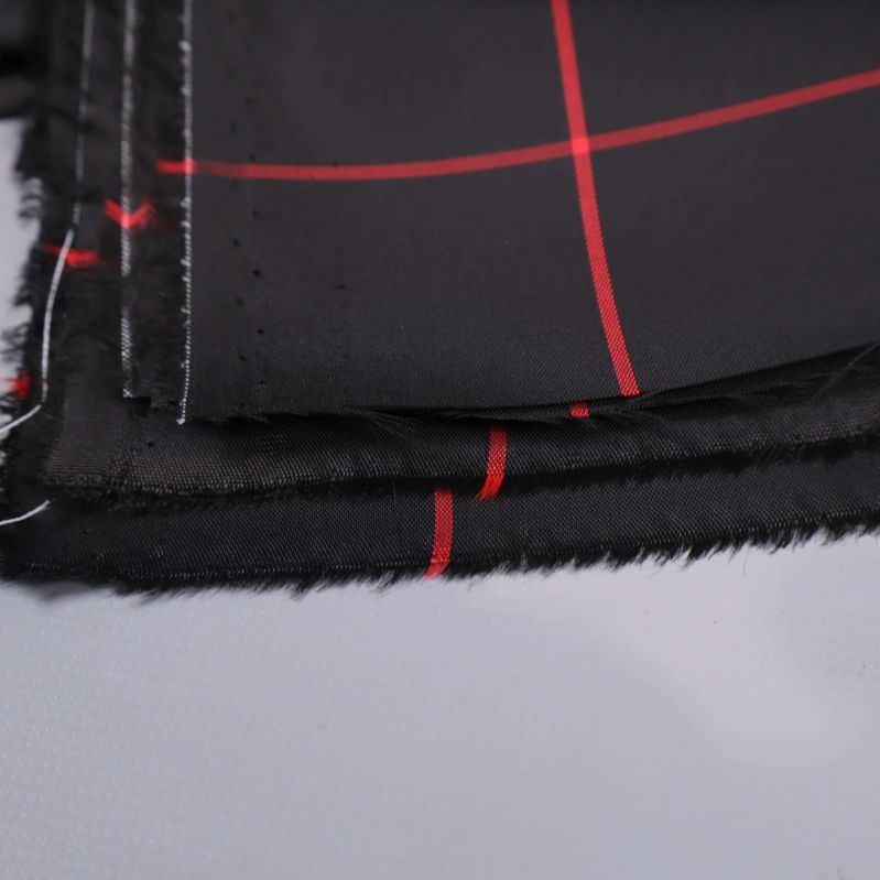 Närbild av rå kant på svart tyg med röda rutor