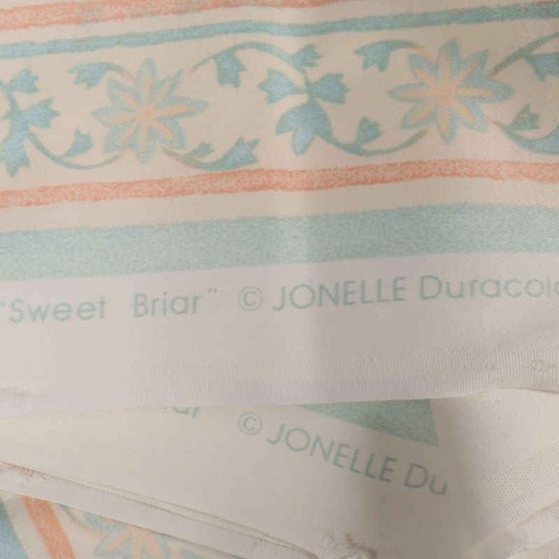 Text med designnamn och tillverkare på gardinens kant