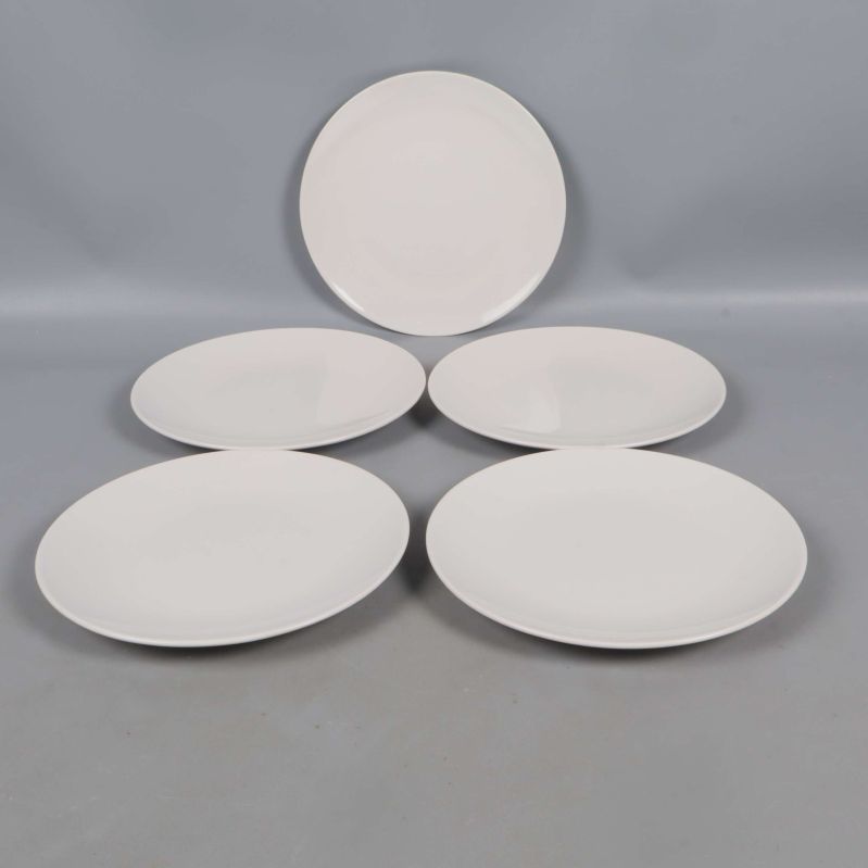 Fem vita tallrikar utspridda på grå yta