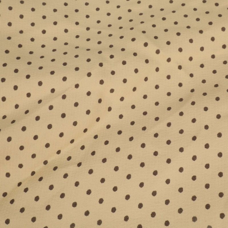 Närbild på beige tyg med bruna prickar