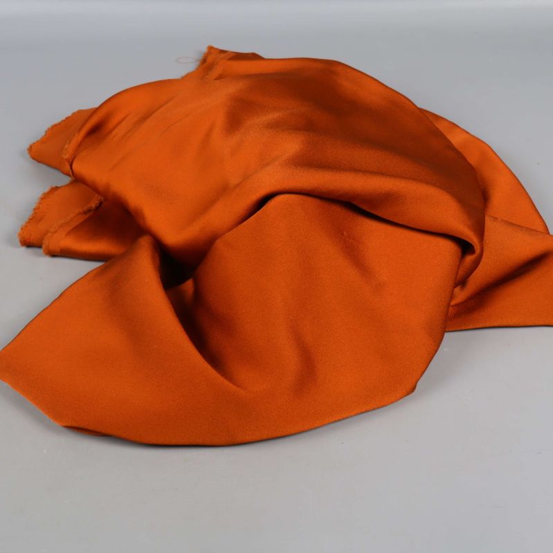 Orange tyg i lös hög med blanka partier
