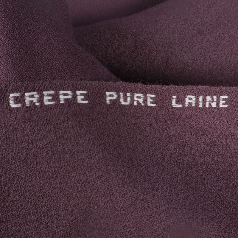 Kant av tyg med texten crepe pure laine
