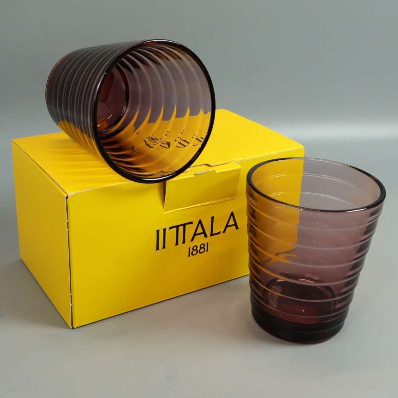 Två räfflade lila glas framför gul Iittala-förpackning