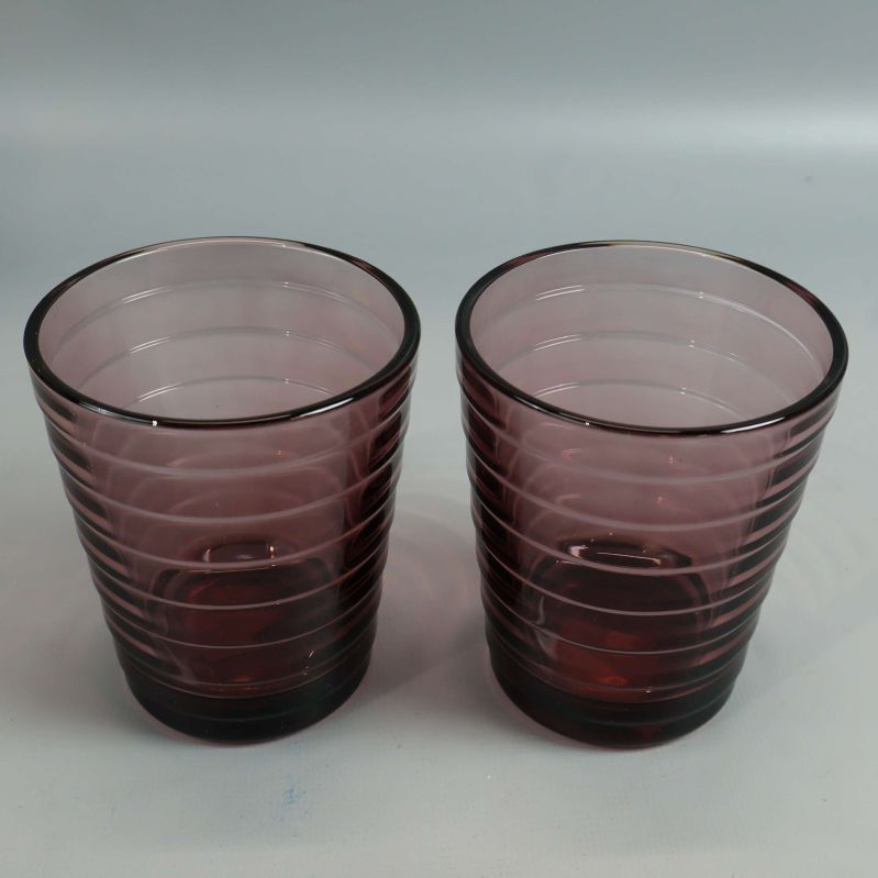 Två lila glas med lätt toning mot grå bakgrund