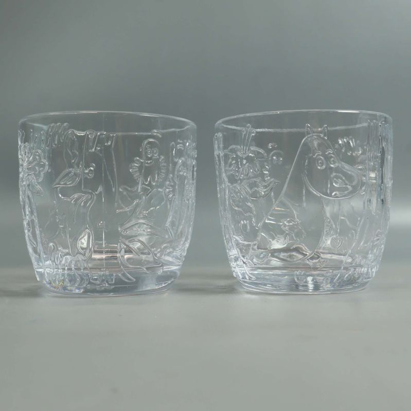 Framifrån: två Mumin-glas med reliefer