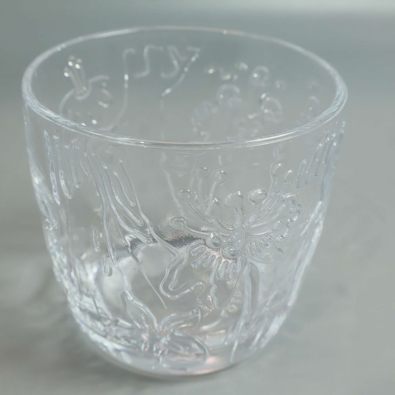 Närbild på ett annat glas med blommor och Muminmotiv