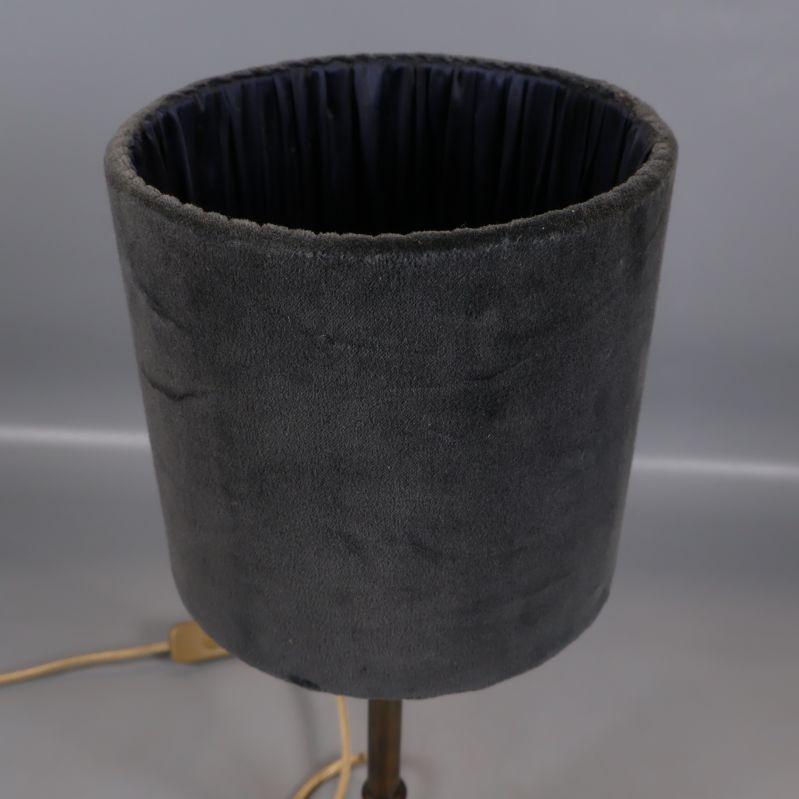 Närbild på grå cylinderformad lampskärm i sammet