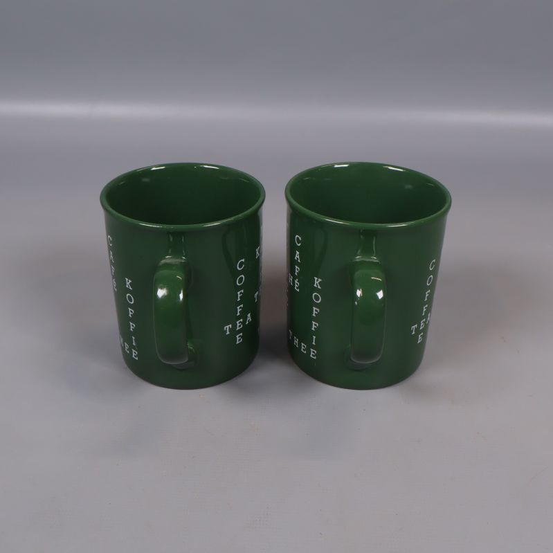 Baksidevy av två gröna kaffekoppar med handtag