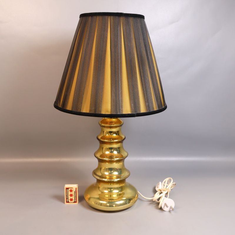 Bordslampa i guld med vit elkabel och tändsticksask bredvid
