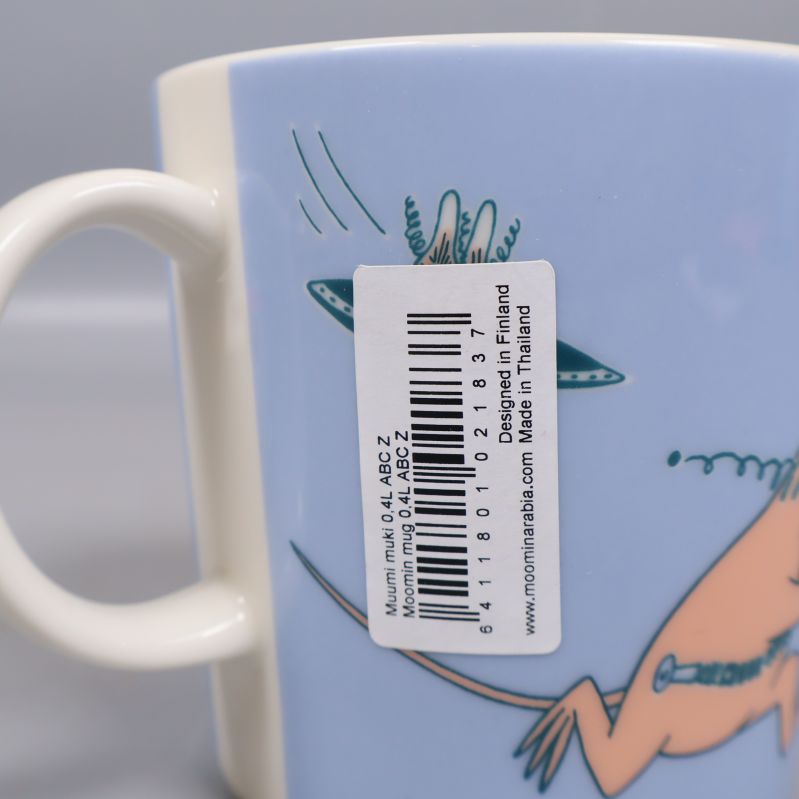 Detalj på etikett med text om Muminmugg och tillverkning