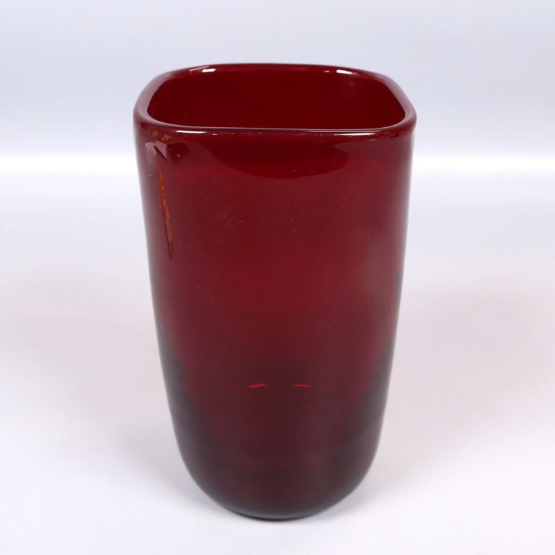 Röd glasvas sedd snett framifrån med fyrkantig öppning