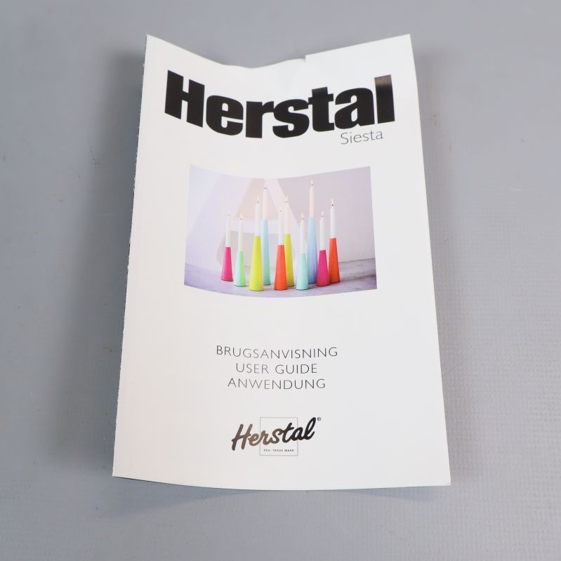 Manual med Herstal logotyp och ljusstakebilder på omslaget