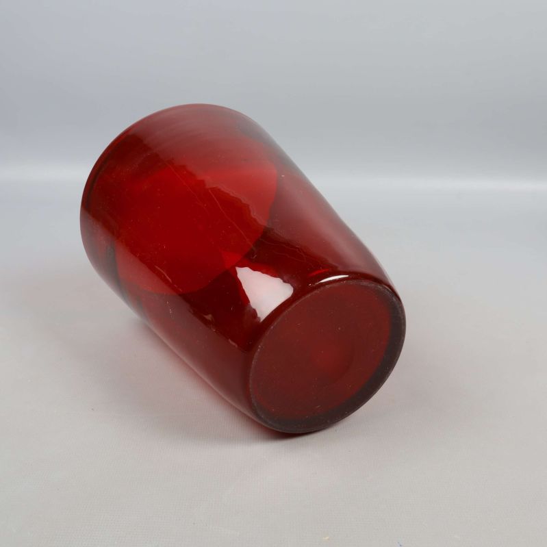 Röd glasvas liggande och visad från sidan
