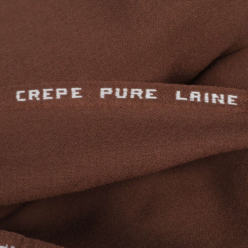Närbild på tyg med texten 'CREPE PURE LAINE'