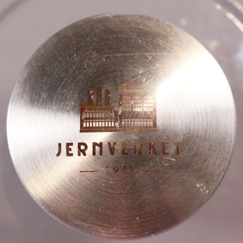 Detaljbild på metallknopp med Jernverket-logo ovanpå locket
