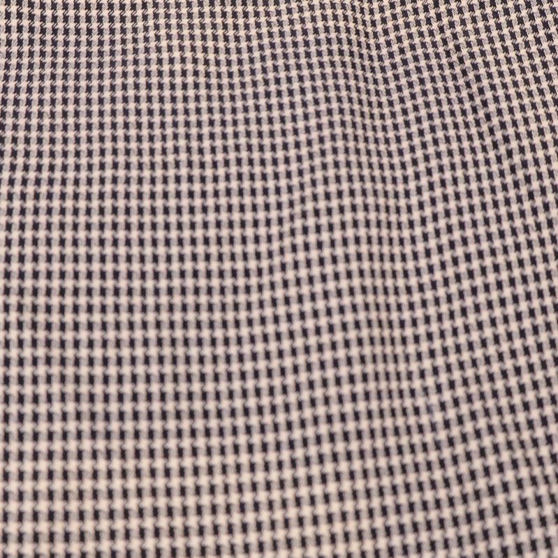 Närbild av tyg med tätt smått rutmönster i beige och svart