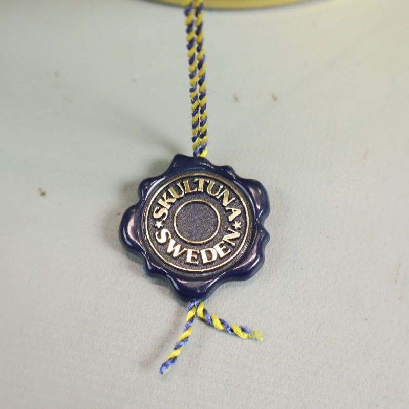 Närbild på Skultuna sigill hängande från burkens handtag