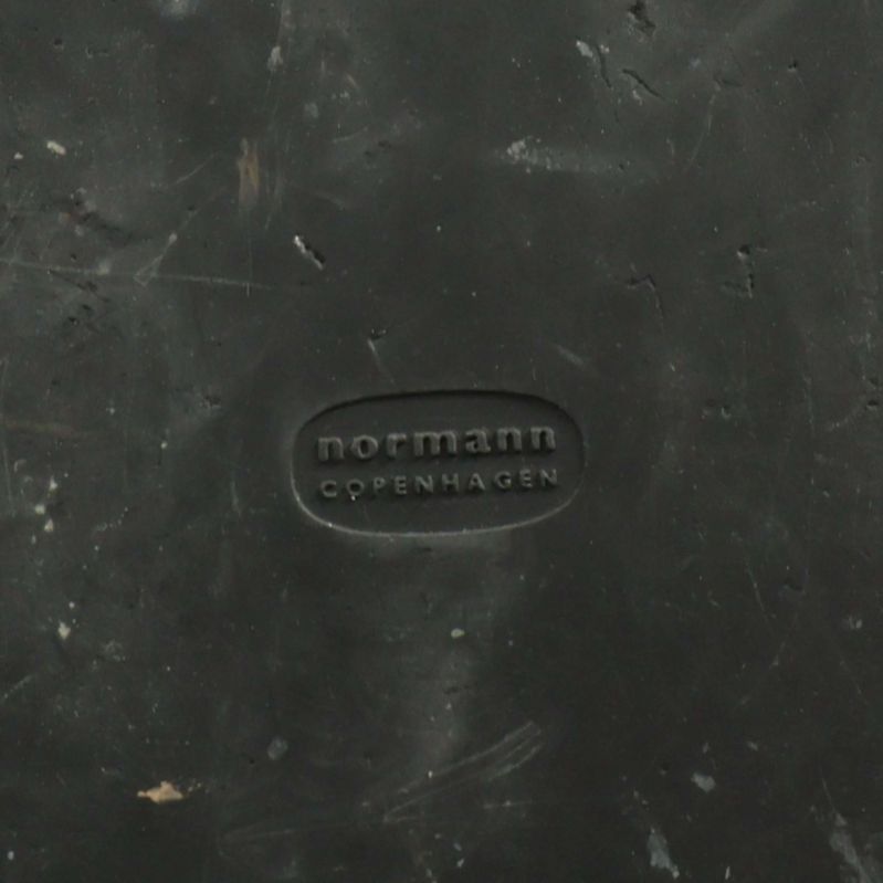 Närbild av Normann Copenhagen logotyp på svart underlag