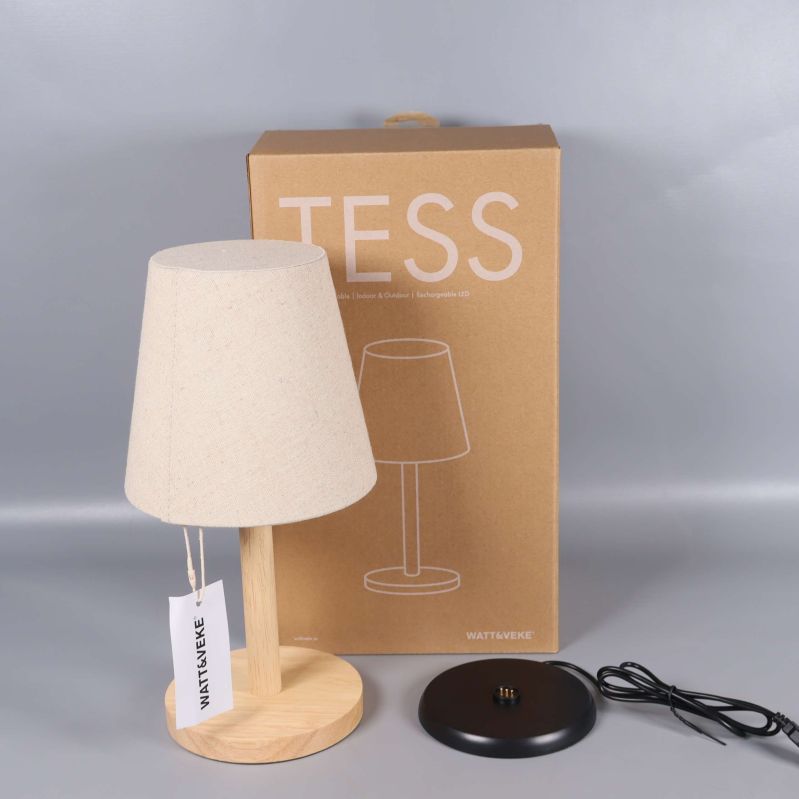 Bordslampa med träfot framför kartong med texten TESS