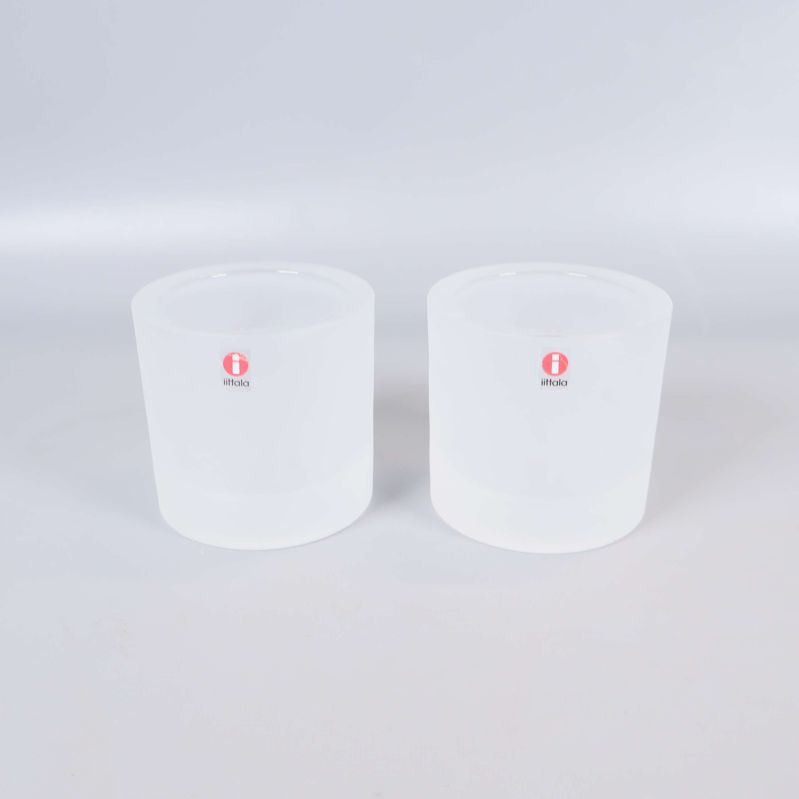 Framifrån på två vita glaslyktor med Iittala-logga