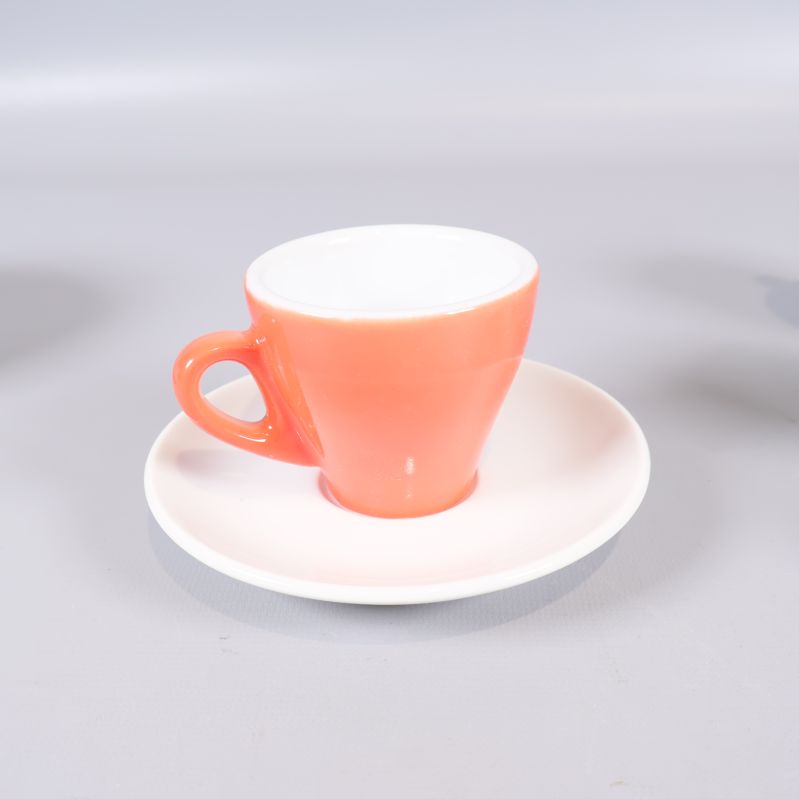 Närbild på espressokopp och fat i korallfärg