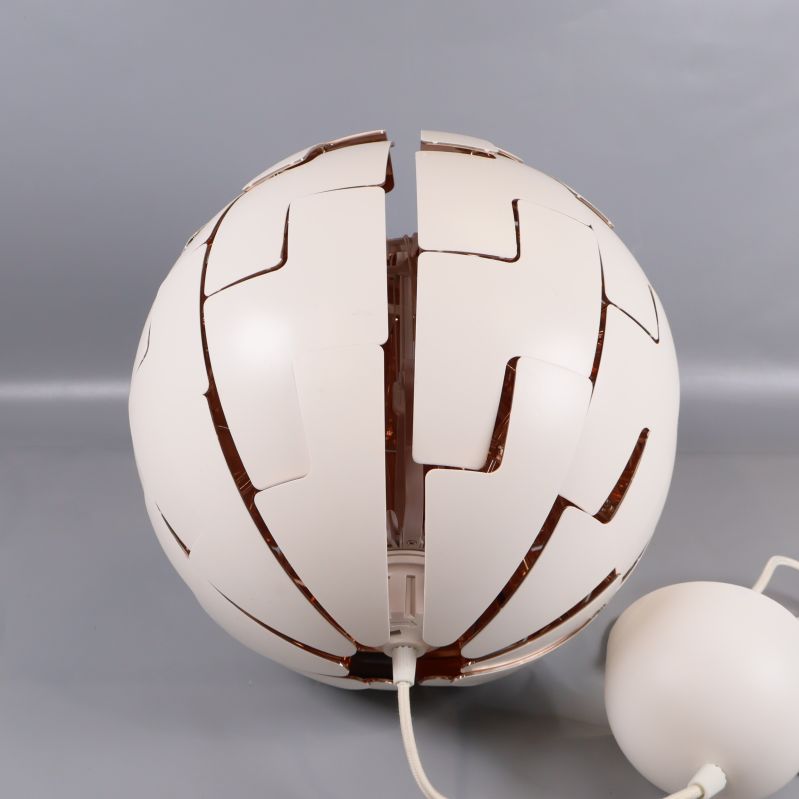 Närbild på lampa med öppning i mitten och vit kopparfärgad design