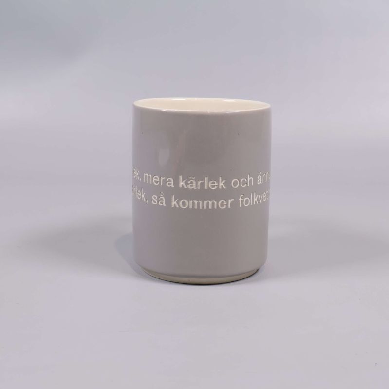 Grå mugg fotograferad rakt framifrån med citat