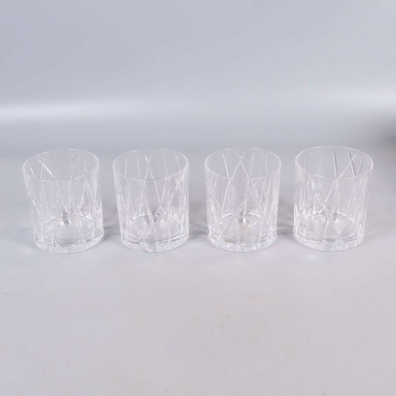 Fyra slipade whiskeyglas i rad på ljus yta