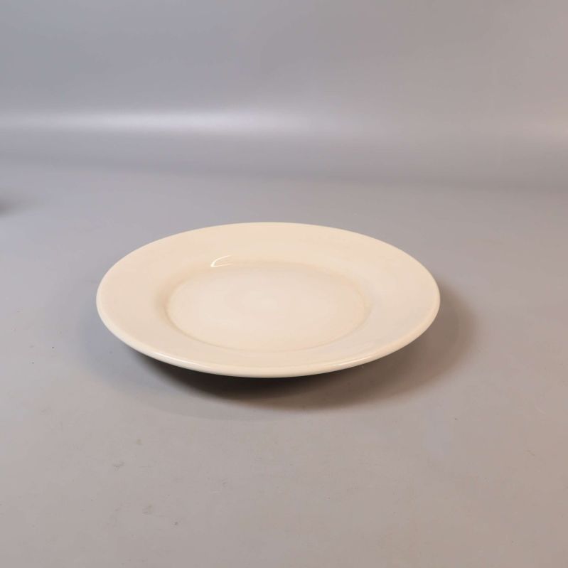 Krämvit tallrik i sidovy mot ljus bakgrund