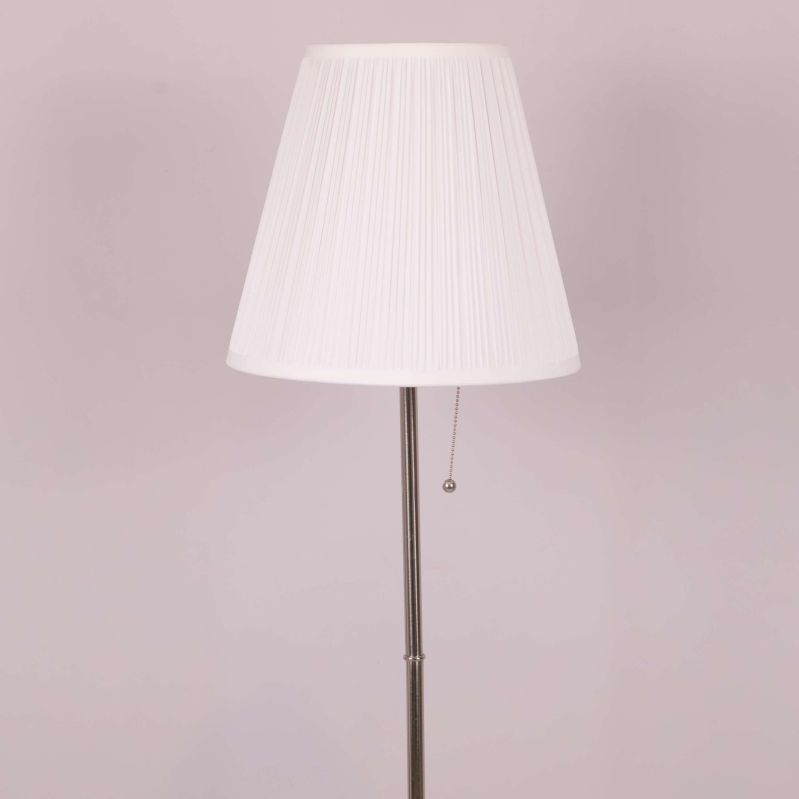 Närbild på veckad vit lampskärm och metallstång