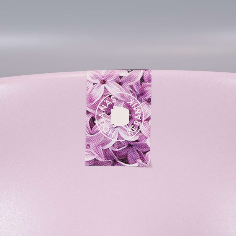 Närbild av etikett med lilamönstrade blommor och logotyp