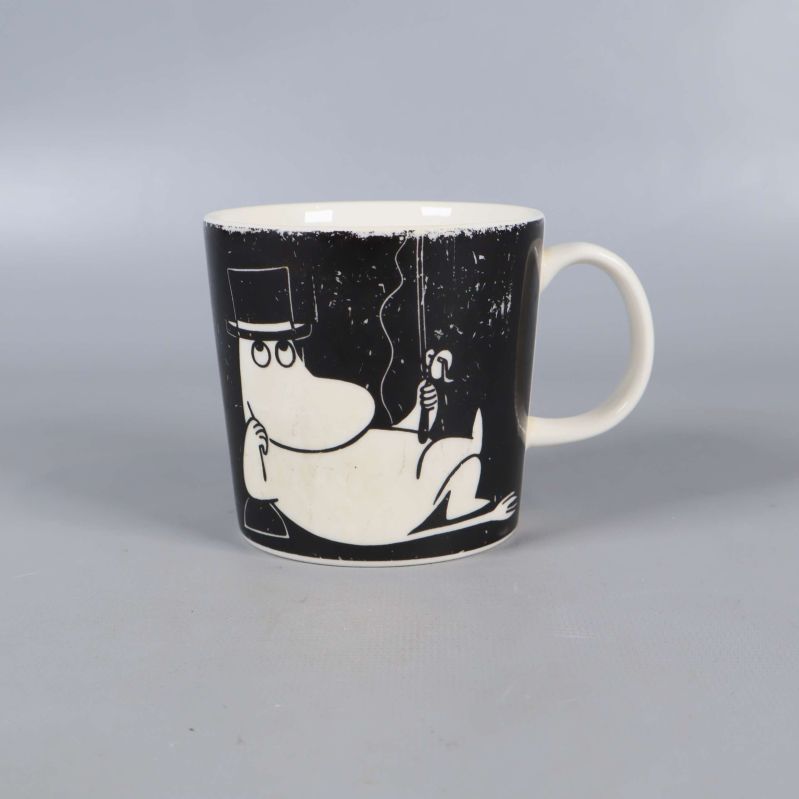 Svart mugg med muminmotiv och vitt handtag