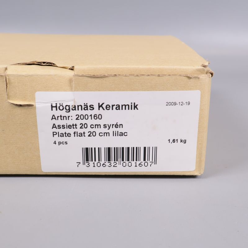 Kartong med etikett som visar Höganäs Keramik assietter 20 cm syren