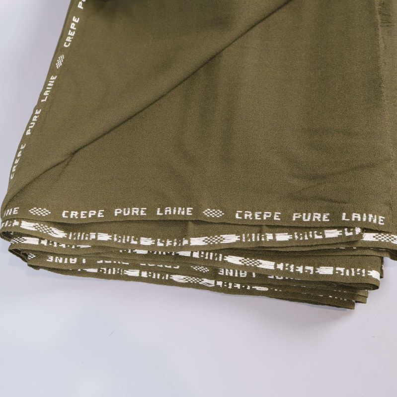 Detaljerad bild av tyg med texten CREPE PURE LAINE