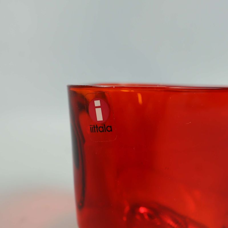 Närbild på Iittala-logotyp på röd ljushållare i glas