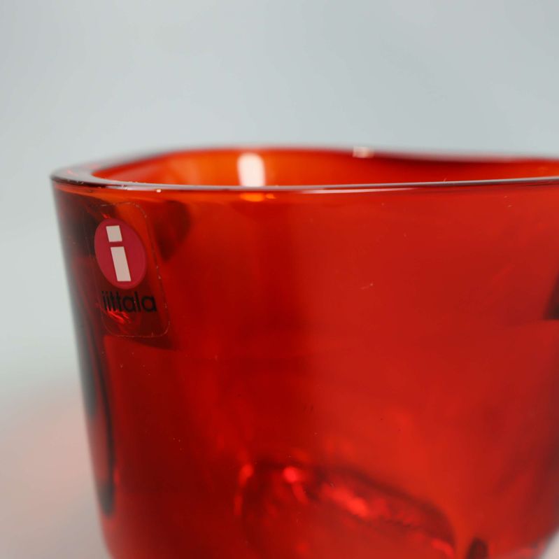 Detalj av kanten på röd glasljushållare med logotyp